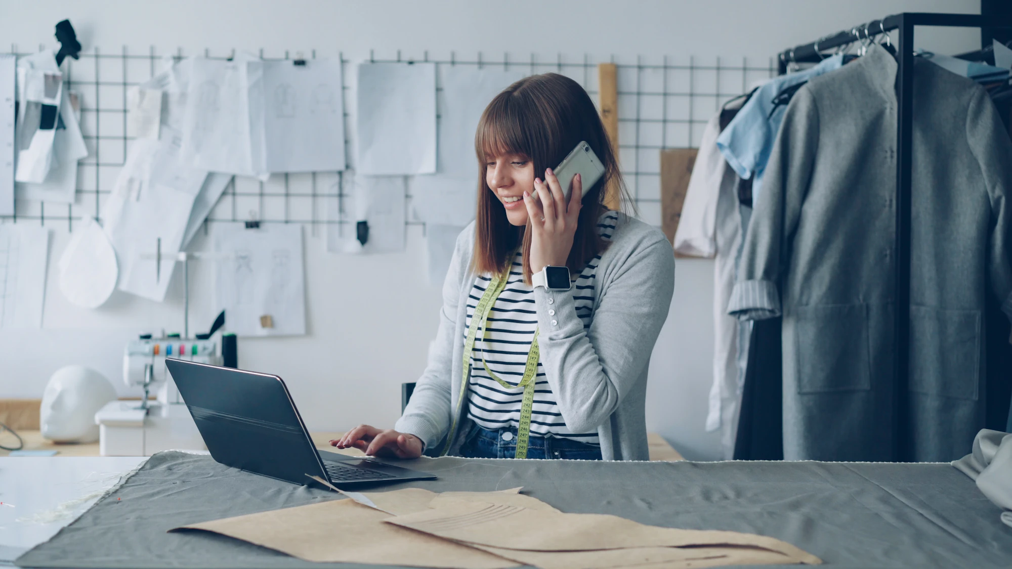 A small business owner on the phone while working at her laptop in her studio