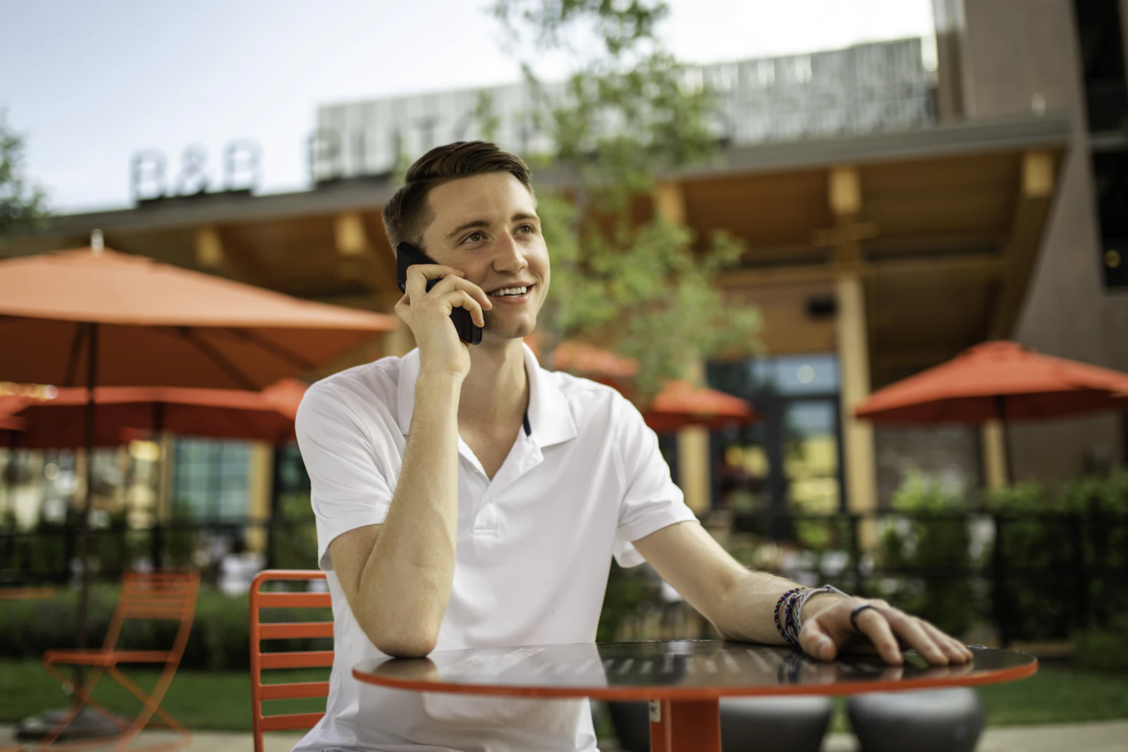A business owner smiling as he takes a call at a cafe patio