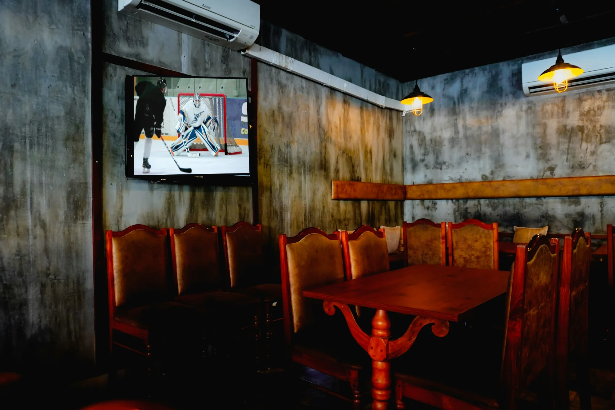 A restaurant with leather booths and a wall TV on a hockey game