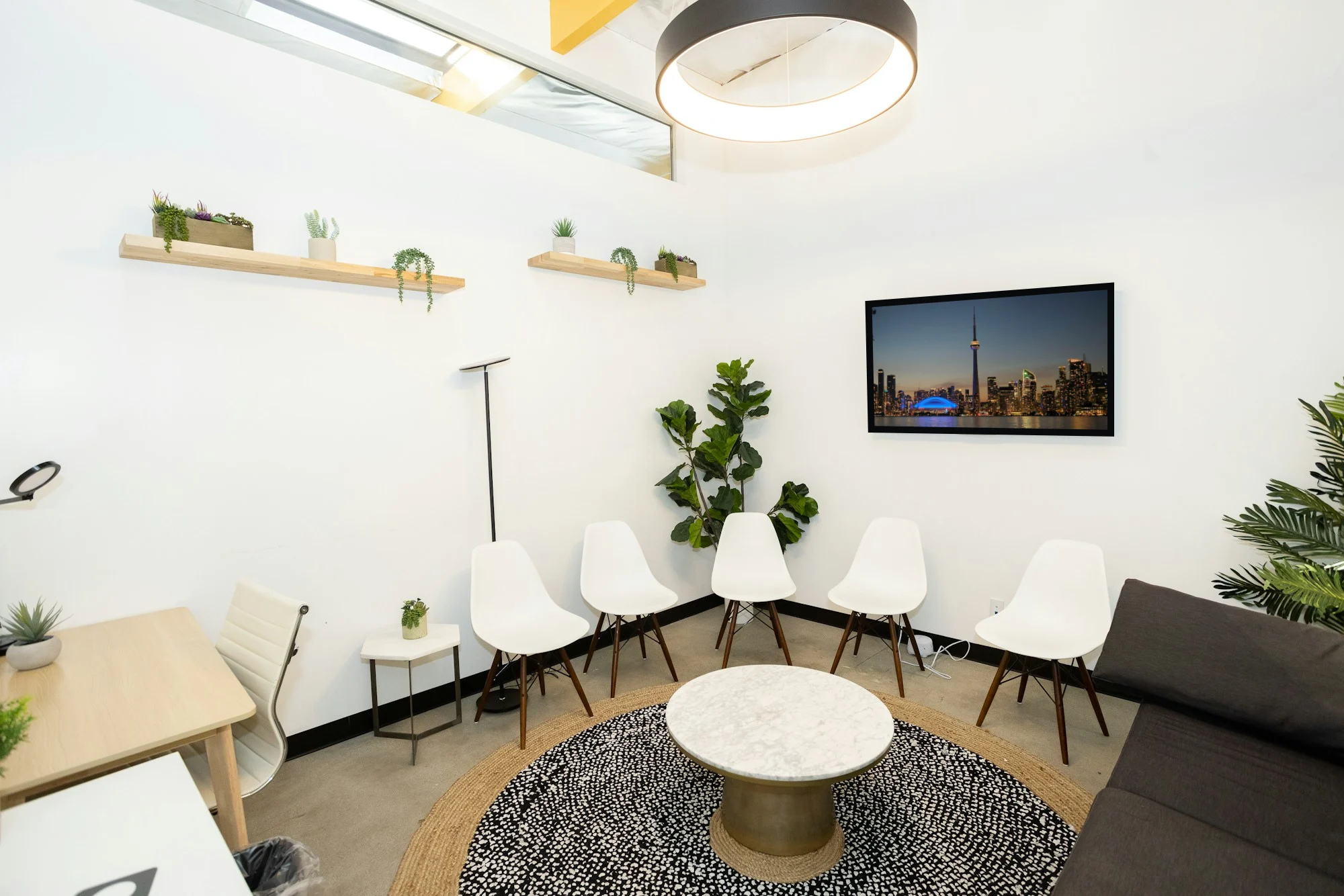 A bright waiting room with white chairs and a wall TV showing the Toronto skyline