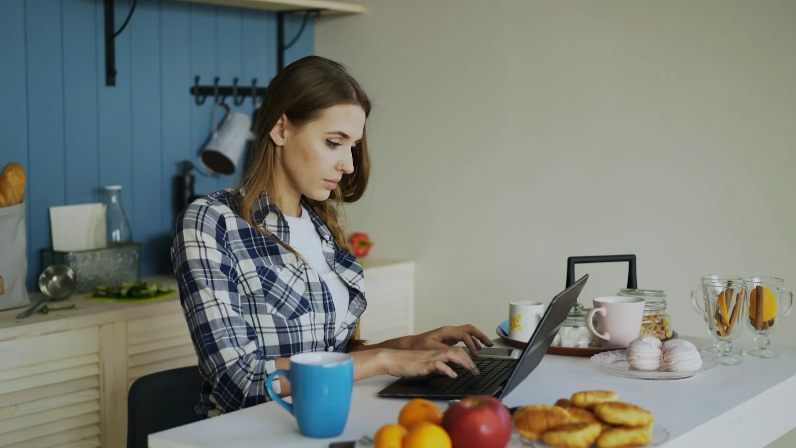 A woman working on her laptop at the kitchen table