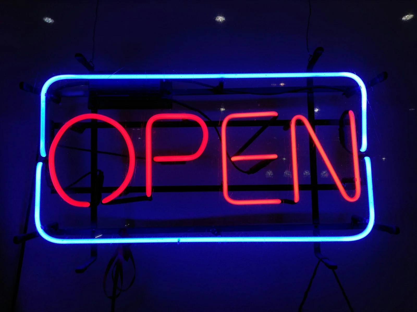 A neon open sign glowing red and blue in the dark